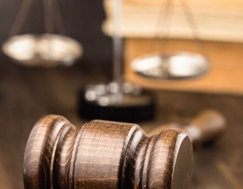 Wooden gavel with scales and books on table vertical